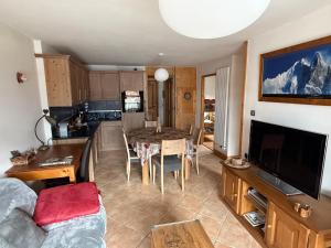 a kitchen and living room with a table and a television at Résidence Les Chardons Argentés in Samoëns