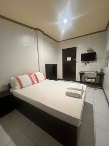 a bedroom with a large white bed with a desk at Optimun Inn in Davao City