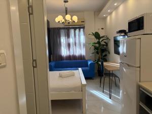 a small room with a blue couch and a kitchen at Rothschild 79 in Petaẖ Tiqwa
