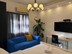 a living room with a blue couch and a desk at Rothschild 79 in Petaẖ Tiqwa