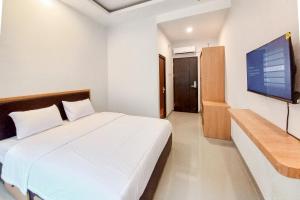 a bedroom with a white bed and a flat screen tv at Sans Vibes Viandara Pekanbaru in Parit