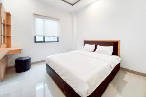 a white bedroom with a large bed and a window at Sans Vibes Viandara Pekanbaru in Parit +23 photos