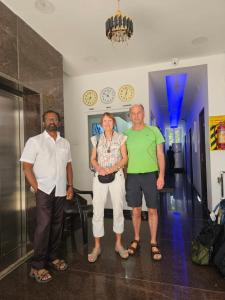 three people posing for a picture in a room with clocks at Metroresidency com - Behind LIC in Chennai