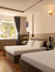 a hotel room with two beds and a window at Phương Châu Holiday Hotel Đà Lạt in Da Lat +33 photos