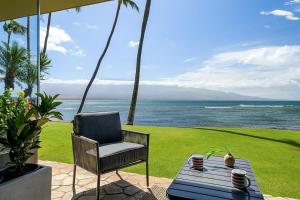 a chair and a table with a view of the ocean at Lauloa 106 in Wailuku