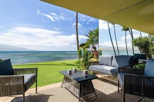 a patio with a table and chairs and the ocean at Lauloa 106 in Wailuku