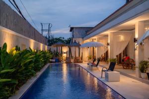 a pool with chairs and umbrellas next to a building at Santai Suites Nusa Dua in Nusa Dua
