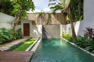 a swimming pool in the backyard of a house at Du Ciel Villa by Betterplace in Canggu