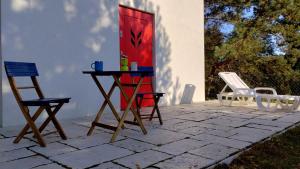 a patio with two chairs and a table and a red door at Chata z Kraja in Józefów