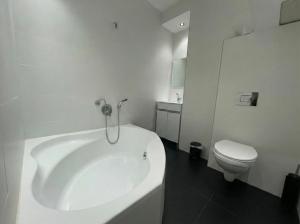 a white bathroom with a tub and a toilet at Rothschild 79 in Petaẖ Tiqwa +15 photos