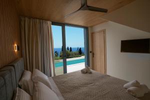 a bedroom with a bed and a large window at Avithos Blue Villas in Svoronata +78 photos