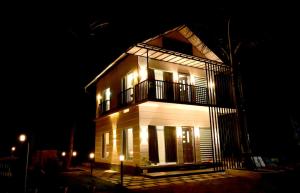 a large white building with a balcony at night at Shade trees in Padinjarathara