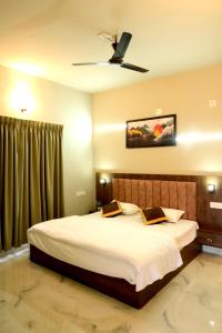 a bedroom with a large bed with a ceiling fan at Shade trees in Padinjarathara