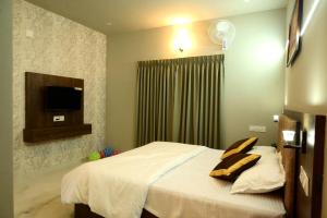 a bedroom with a bed with pillows and a television at Shade trees in Padinjarathara