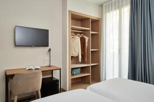 ein Schlafzimmer mit Schreibtisch, Bett und Fernseher in der Unterkunft Hostal Centric in Barcelona