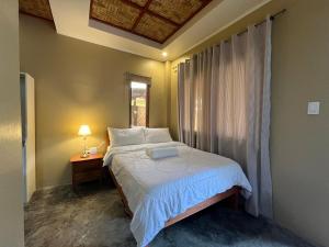 ein Schlafzimmer mit einem weißen Bett mit einem Fenster und einem Tisch in der Unterkunft Bitang's Guesthouse - Starlink Ready in Burgos