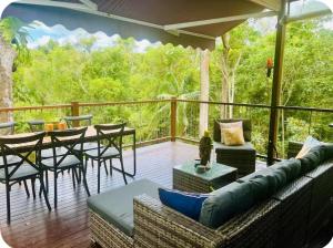 a deck with a couch and a table and chairs at Addisons Baroon A Rainforest Retreat with Heated Plunge pool in Montville