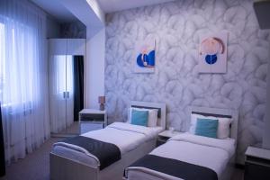 a hotel room with two beds and a wall at Tengri Hotel in Aktau