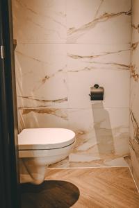 a bathroom with a white toilet and marble walls at Hotel Centraal Baarlo in Baarlo