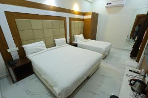 two beds in a hotel room with white sheets at Hotel Amar Singh Palace in Agra +26 photos