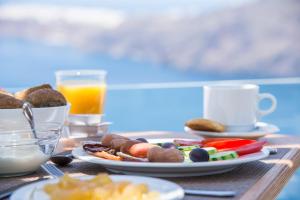 a table with a plate of food and a cup of orange juice at Gizis Cliffside Suites in Imerovigli