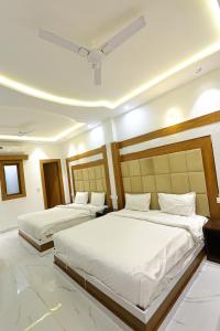 two beds in a hotel room with white sheets at Hotel Amar Singh Palace in Agra