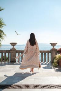 a woman walking along a fence near the ocean at Amadria Park Hotel Milenij in Opatija