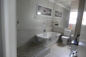 a white bathroom with a tub and a toilet at Beach Club Unit 207 in Mossel Bay +44 photos