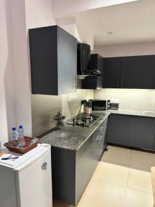 a kitchen with black cabinets and a white refrigerator at Staye Deluxe 2BHK in Islamabad