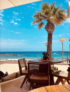 a table with chairs and a palm tree on the beach at Blue Peter Apartments in Protaras