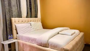 a bed in a room with a yellow wall at Kigombe River Motel- musanze in Ruhengeri