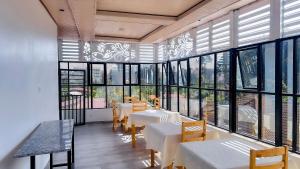 a restaurant with tables and chairs and large windows at Kigombe River Motel- musanze in Ruhengeri