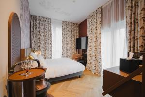 a bedroom with a bed and a desk and a television at Hota Hotel Porrentruy in Porrentruy +59 photos