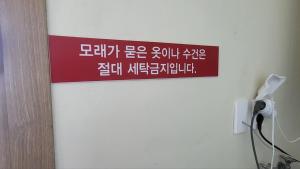 a red sign on a wall with writing on it at Jeju Dalbit Pension in Jeju