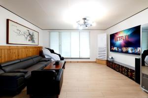 a living room with a couch and a television at Jeonju Dalbitsori Pension in Jeonju