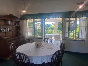 a dining room with a table and chairs and windows at BillsBest Greengates Cottages in Port Edward