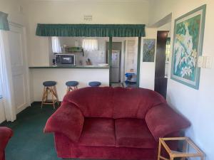 a living room with a red couch and a kitchen at BillsBest Greengates Cottages in Port Edward +26 photos
