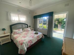 a bedroom with a bed and a large window at BillsBest Greengates Cottages in Port Edward