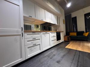 a kitchen with white cabinets and a couch in a room at Apartament Centrum 19 in Nowy Sącz +5 photos