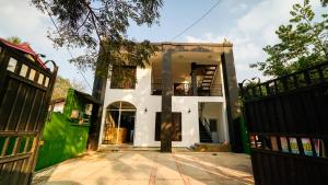 a white house with a gate and a building at Pearl Guest House in Dambulla