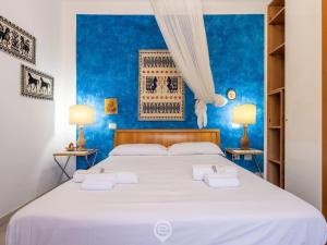 a bedroom with a large white bed with blue walls at Estay - Villa Foxi Serenity - Exclusive holiday in Quartu SantʼElena