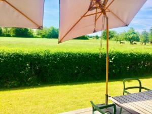 un tavolo e sedie con un ombrellone e un campo di simsseeLOFT - Ferienapartments in Baierbach am Simssee a Stephanskirchen