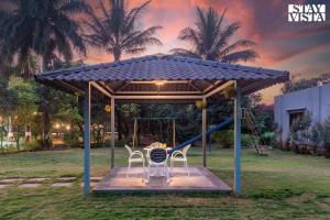 a playground with two chairs and a swing at Hindavi Green Escape by VEO - Part of StayVista with Bonfire, BBQ & Pool in Pune