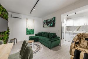 a living room with a green couch and a kitchen at Green Luxe Suite 1 by PikHost in Shkodër