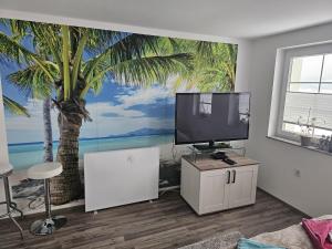 a living room with a tv and a palm tree mural at Kuća NADA in Donja Voća