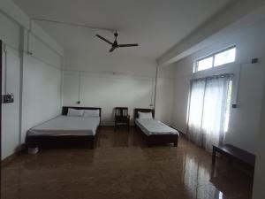 a bedroom with two beds and a ceiling fan at Devagram Guest house in Dergaon