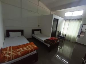 a room with two beds and a window in it at Devagram Guest house in Dergaon