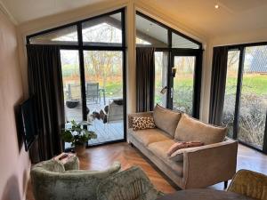 a living room with a couch and chairs and a television at Tiny House 'Het Chalet' in Berlicum