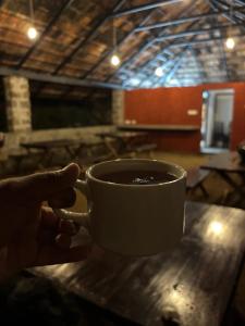 a person holding a cup of coffee on a table at Deshadan Jungle in Kanthalloor