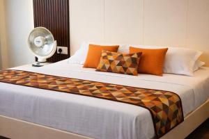 a bedroom with a bed with a fan and pillows at Mandola Stays in Girgaon